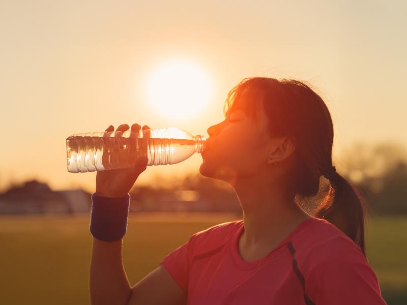 Woman drinking a bottle water on a hot sunny day